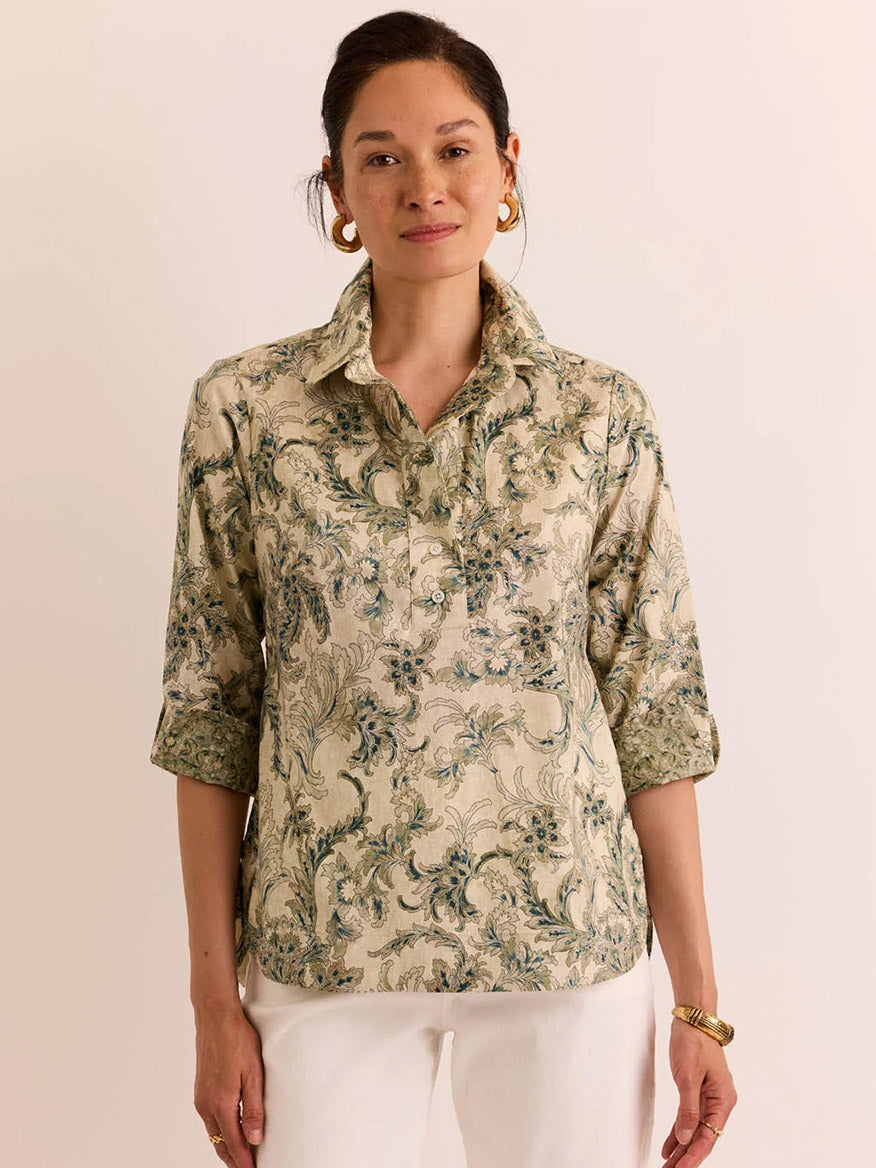 A woman wearing the Hinson Wu Charlotte 3/4 Sleeve Fresco Print Top—a light-colored, patterned blouse featuring a premium cotton blend with a collar and three-quarter sleeves—paired with white pants, stands against a plain background.