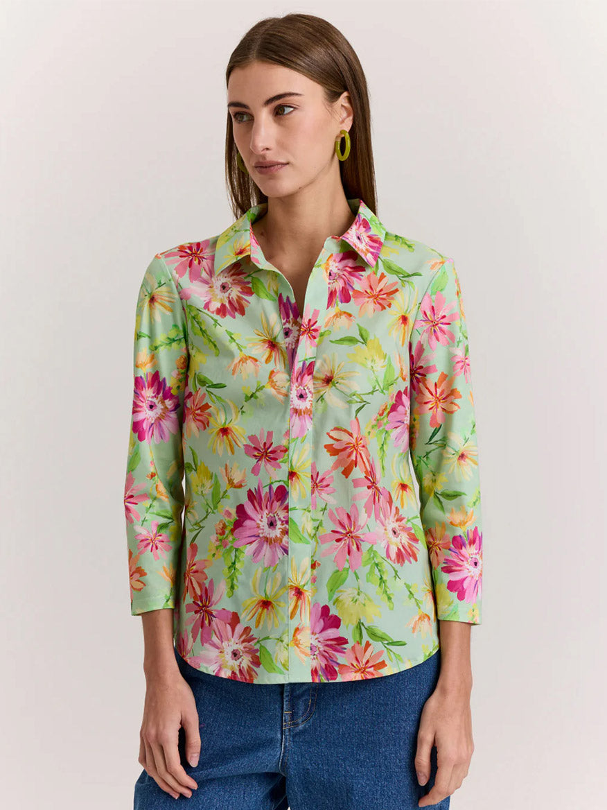 A woman wears the Hinson Wu Lizette 3/4 Sleeve Green Floral Print Top, featuring a light green floral pattern and premium cotton knit, paired with blue jeans.