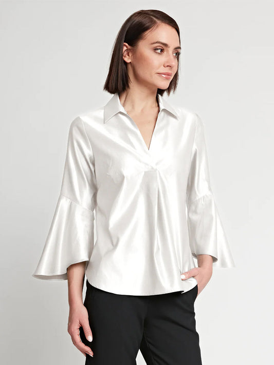 Woman in a studio wearing a Hinson Wu Nicole Bracelet Sleeve Silk Satin Top in Cloud with black trousers, looking to the side.