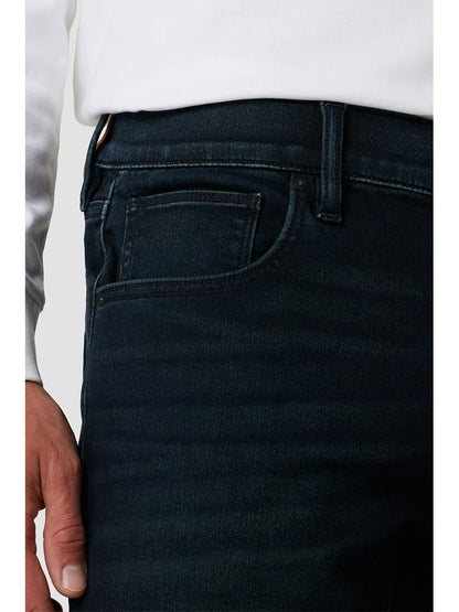 Close-up of a person wearing dark indigo Hudson Blake Slim Straight Jeans in Hayworth with a hand in the pocket.