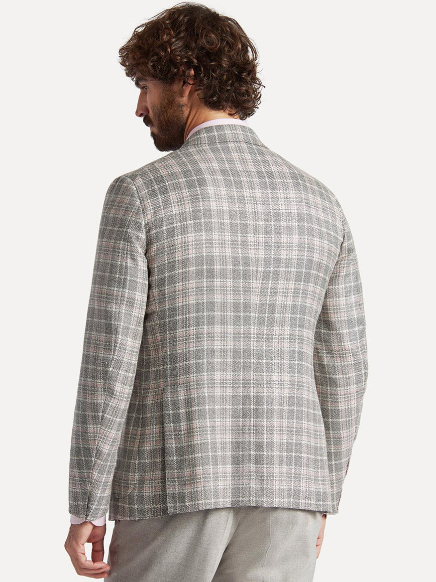 A man is shown from the back, wearing a Isaia Capri Sport Jacket in Rustic Grey with Cream/Pink Plaid and light-colored trousers by Isaia, Capri, Italy.