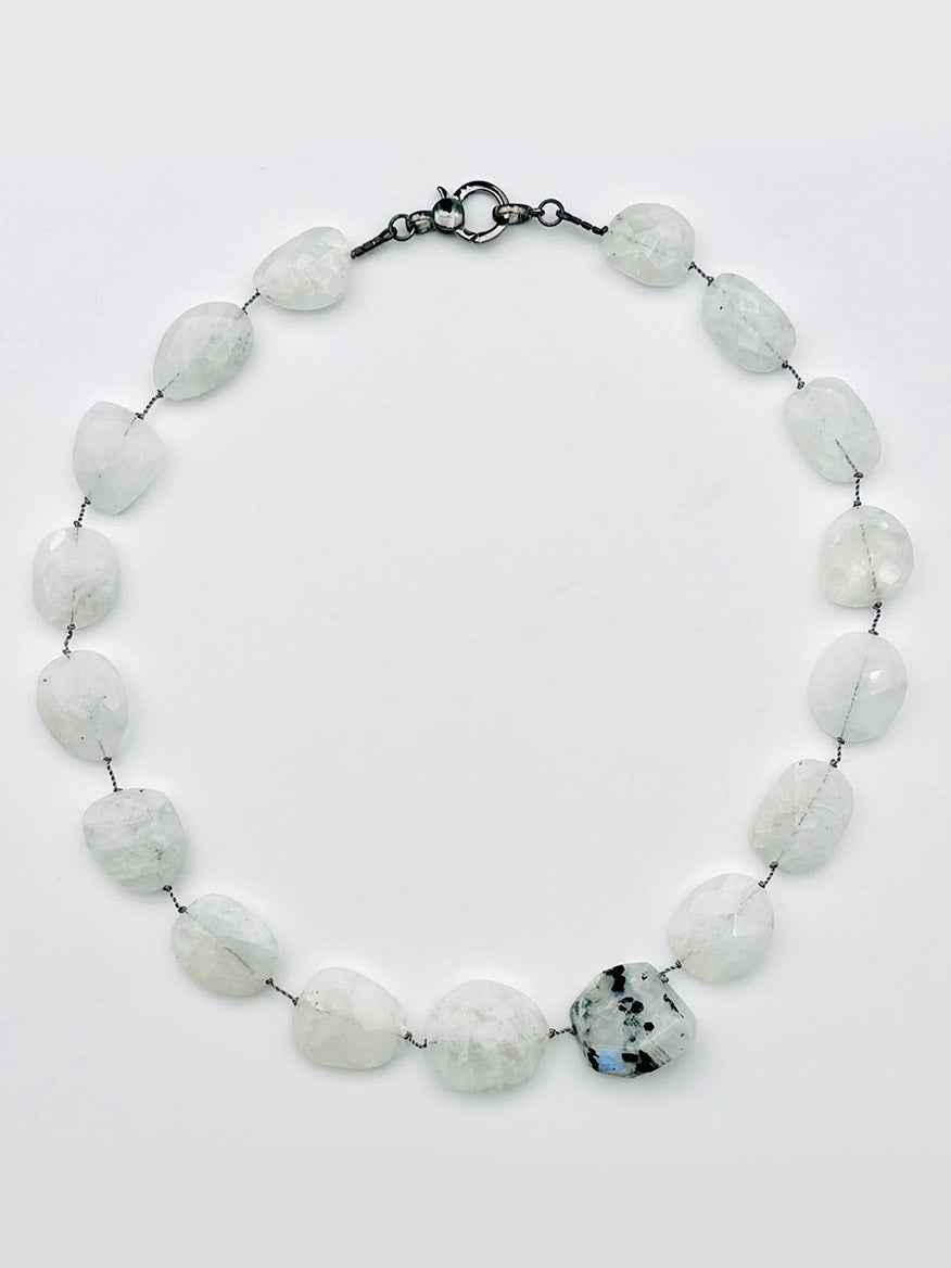 JMNYC Designs 18" Flat Faceted Rainbow Moonstone Necklace, showcasing irregular white stones and a larger faceted moonstone with black speckles, all connected by visible wire and finished with a sterling silver clasp, displayed on a light background.