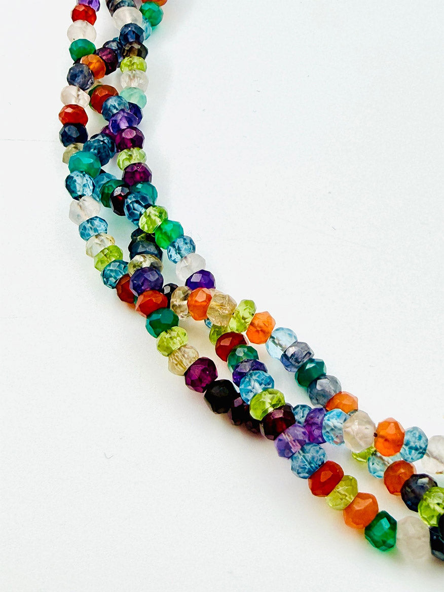 Three strands of faceted, round, multicolored glass beads are arranged diagonally against a plain white background, creating an elegant display reminiscent of the JMNYC Designs 18" Triple Strand Faceted Multi Stone Necklace.