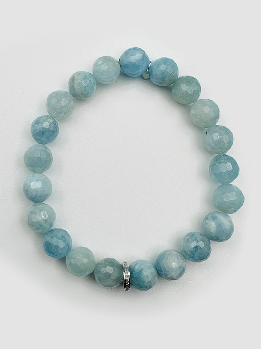 The JMNYC Designs Faceted 8mm Aquamarine Ball Stretch Bracelet features light blue stones and a bright sterling silver diamond rondelle, elegantly arranged in a circle on a white background.