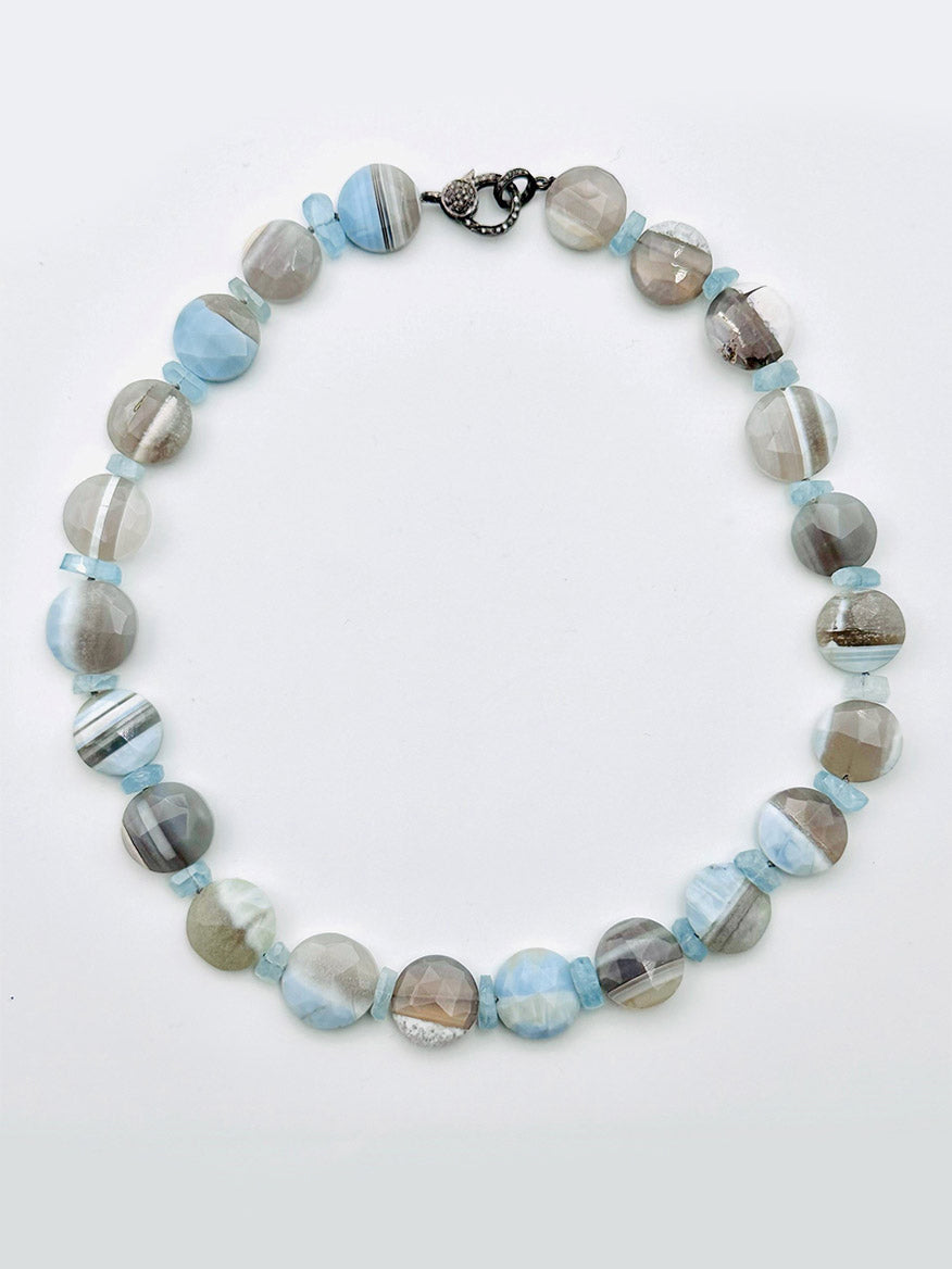 Presenting the JMNYC Designs Coin Blue Boulder Opal Necklace with Aquamarine Slices, featuring round, polished Blue Boulder Opal stones and aquamarine slices in shades of blue, gray, and white, elegantly finished with a sleek sterling silver clasp.