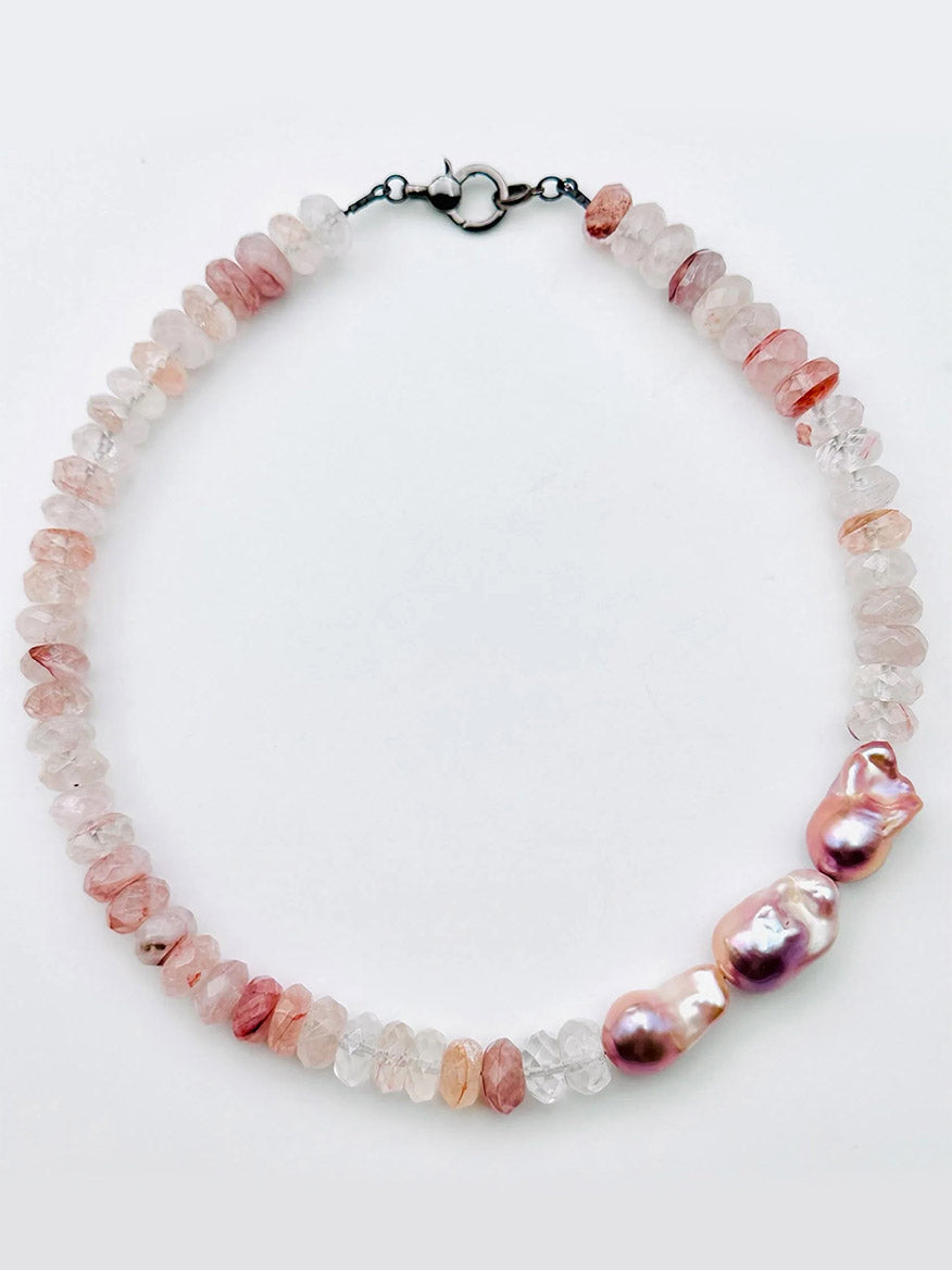Certainly! Here is a rewritten sentence using your provided product data: The JMNYC Designs Faceted Strawberry Quartz Rondell & Natural Baroque Pearl Necklace features pink and clear faceted stones reminiscent of strawberry quartz, accented by three large, irregular pink baroque pearls and finished with a sleek silver clasp.