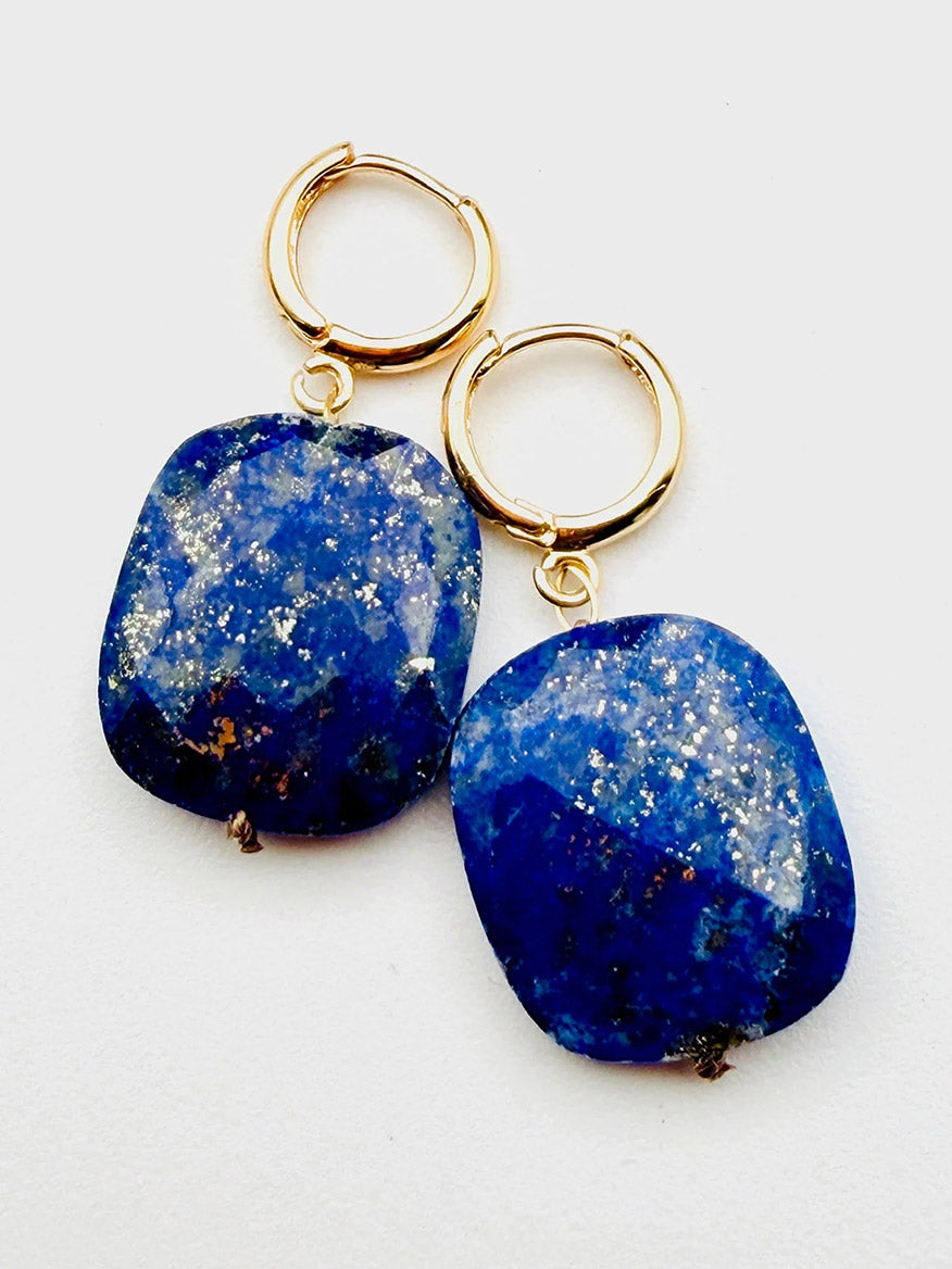 JMNYC Designs Flat Faceted Lapis on Gold Filled Huggie, 1.25" earrings feature square-shaped lapis blue stone pendants with delicate white and gold speckles, displayed on a white background.