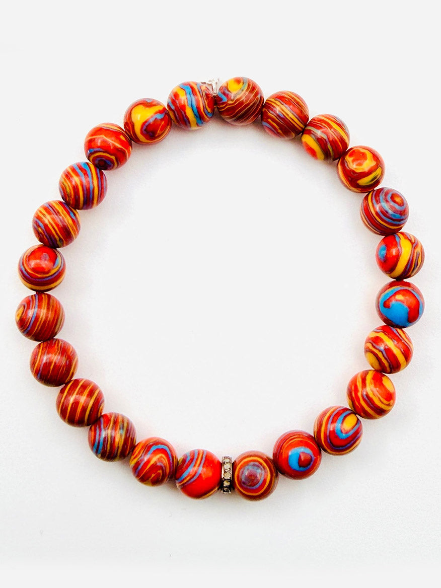 Introducing the JMNYC Designs Graffiti Blue Fordite Ball Bracelet with Diamond Rondelle, 7.25": A vibrant beaded bracelet crafted with round, multicolored red, yellow, and blue marbled Fordite beads—accentuated by a single metallic accent bead and a sparkling Diamond Rondelle. Shown against a white background, this exclusive piece is part of our Limited Edition collection.
