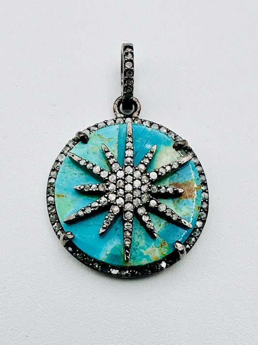 The JMNYC Designs Kingman Turquoise & Diamond Coin Shaped Sterling Silver Pendant features a sun design over a turquoise stone, accented with diamonds, and completed with a coordinating jeweled bail.