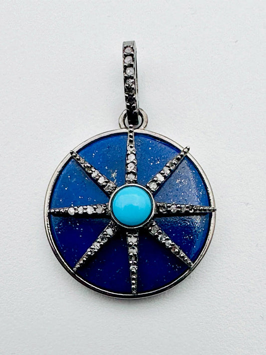 JMNYC Designs Circular Lapis Sterling Silver Pendant features a turquoise and diamond star at the center, encircled by a blue enamel disc with eight gem-studded spokes and a gem-accented bail, shown on a white background.