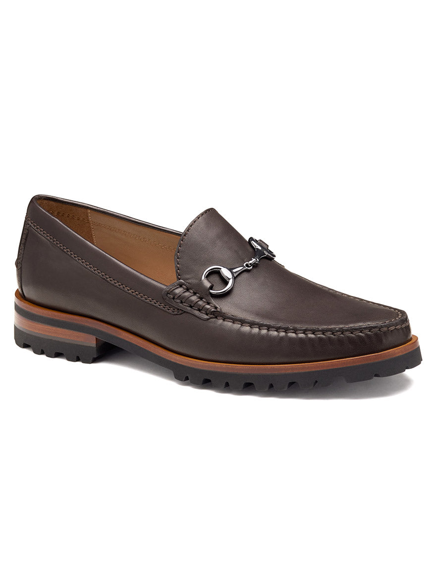 The J & M Collection Baldwin Lug Bit in Dark Brown Sheepskin features handsewn moccasin-style stitching, a silver metal bit, a leather-lined interior, and a treaded rubber sole.