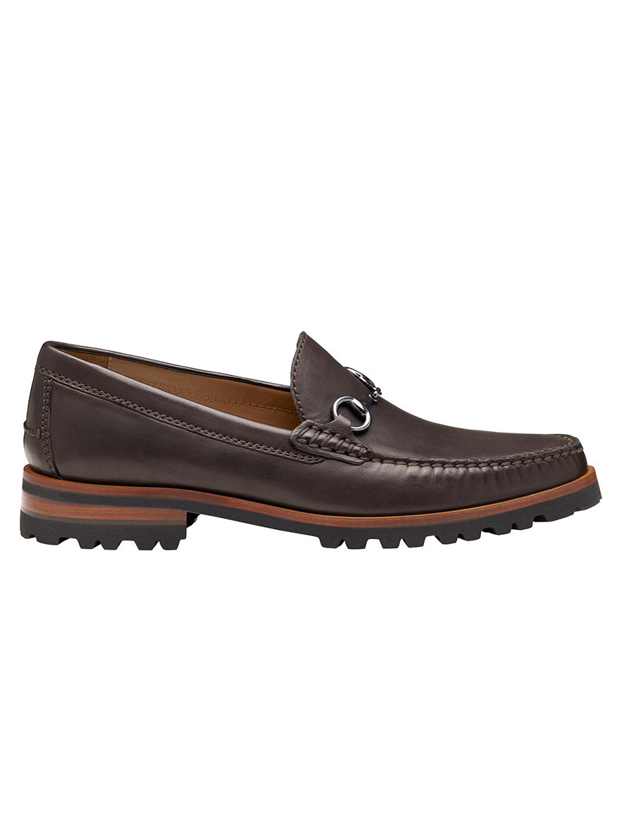 The J & M Collection Baldwin Lug Bit in Dark Brown Sheepskin is a brown loafer with leather lining, metal bit detail, visible stitching, and a chunky black rubber sole featuring a brown accent stripe.