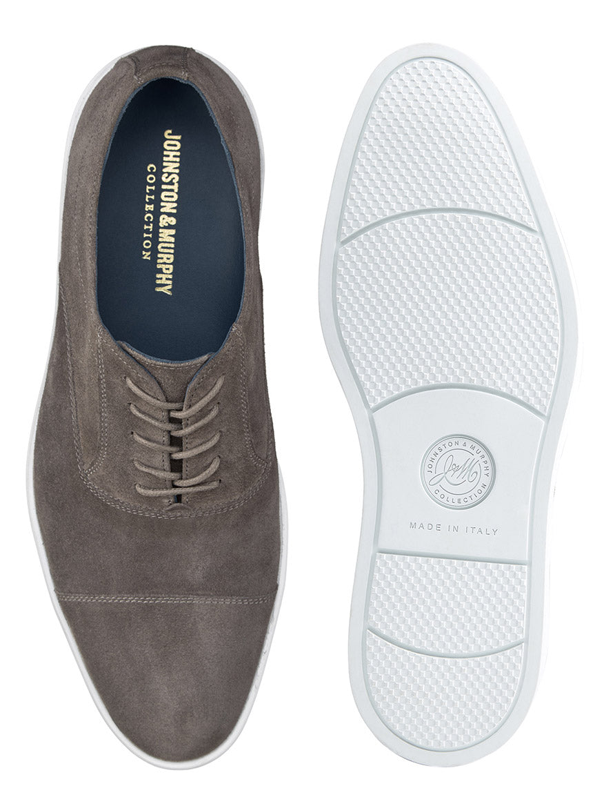 Presenting the J & M Collection Bolivar Cap sneakers in premium gray Italian suede by Johnston & Murphy. These sneakers feature a durable white rubber sole inscribed with "Made in Italy," and include a comfortable, removable footbed. Both top and bottom views are showcased to highlight their design details.