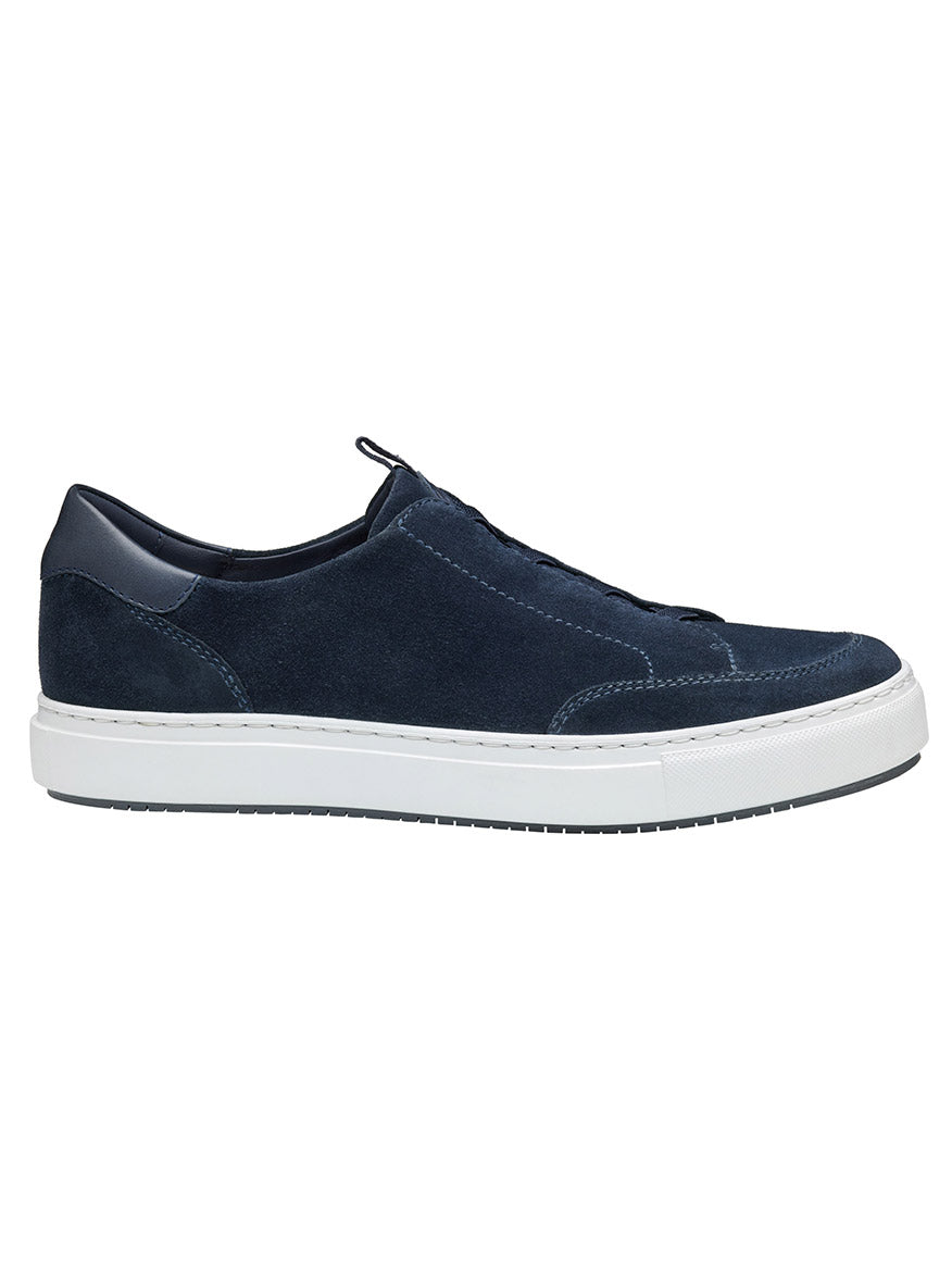 The J & M Collection Anson Stretch Lace-to-Toe is a navy English suede slip-on sneaker with a cushioned footbed, white sole, and seamless design, displayed in side profile.
