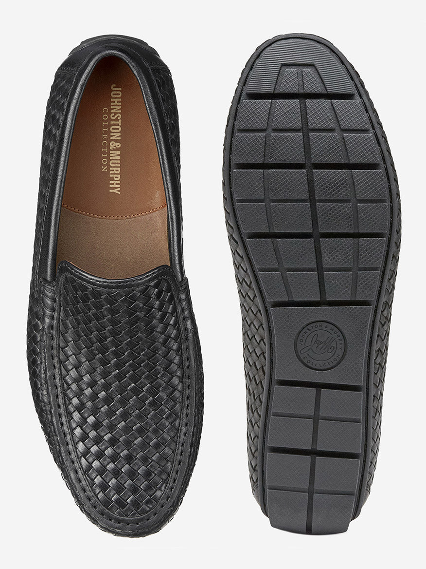 The J & M Collection Baldwin Driver Woven Slip-On in Black Sheepskin showcases a moccasin design with one shoe highlighting the top and the other featuring a grid-patterned sole.