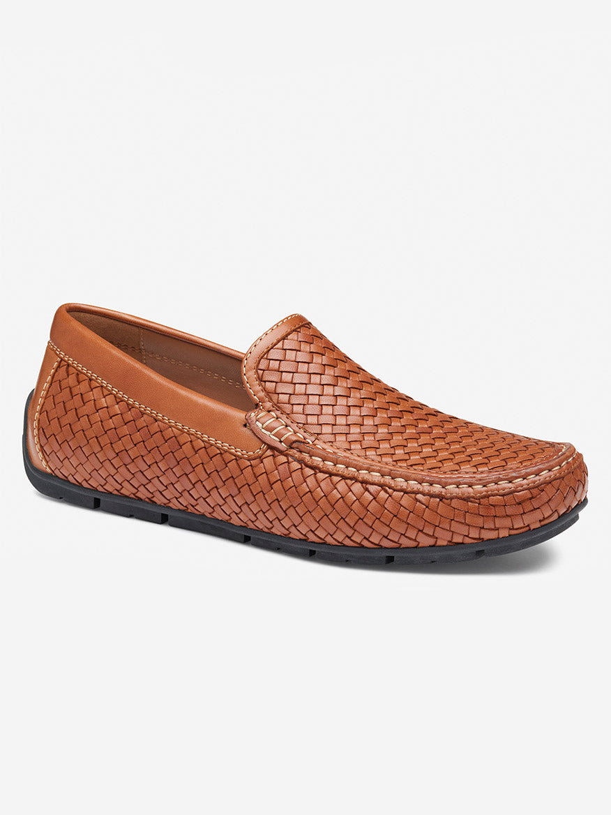 The J & M Collection Baldwin Driver Slip-On in tan sheepskin is a brown woven loafer with a black rubber driver sole, offering a slip-on design and cushioned footbed for ultimate comfort.