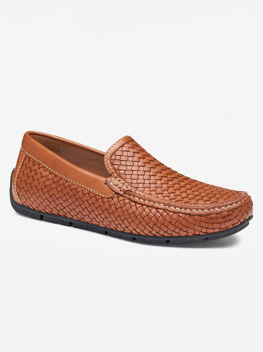 The J & M Collection Baldwin Driver Slip-On in tan sheepskin is a brown woven loafer with a black rubber driver sole, offering a slip-on design and cushioned footbed for ultimate comfort.