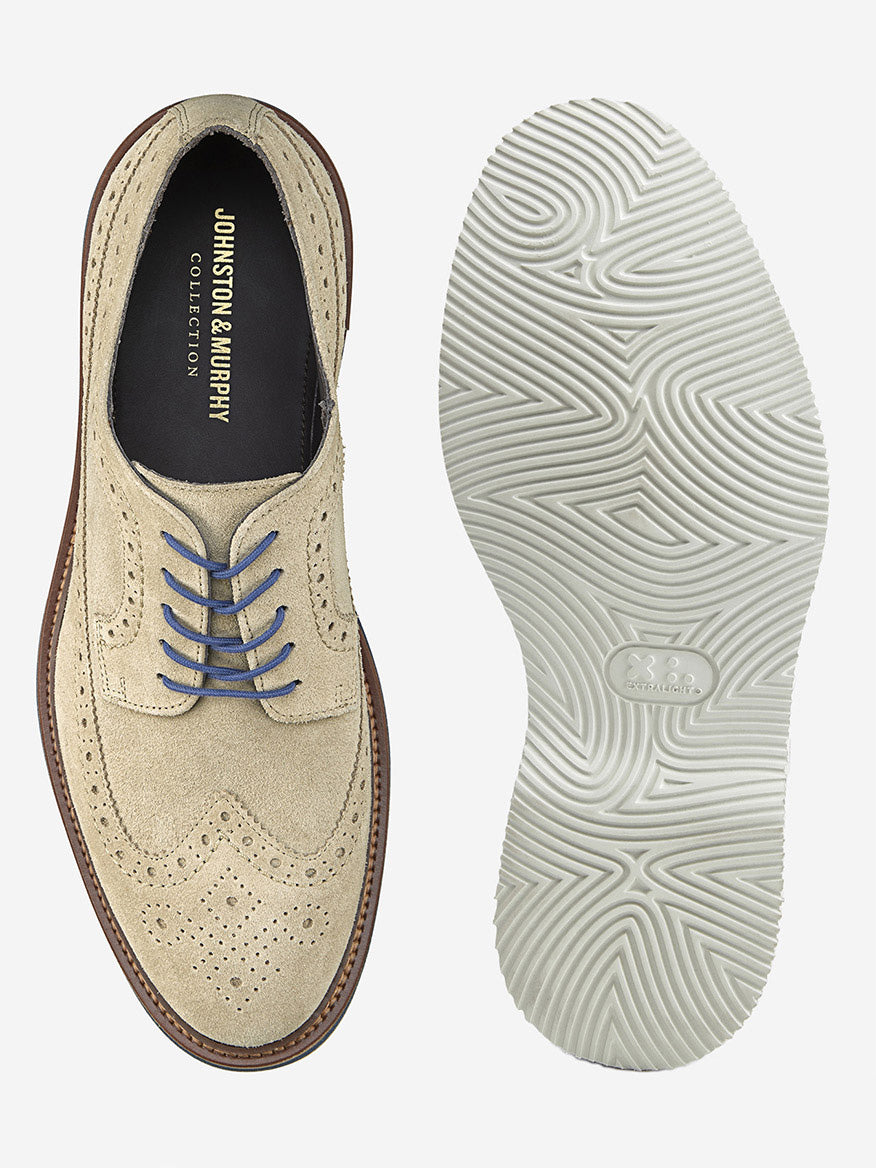 A taupe Italian suede J & M Collection Jenson Longwing, adorned with blue laces and featuring a wavy EVA sole for comfort, has an interior label that reads "Johnston & Murphy Collection," echoing its elegance.