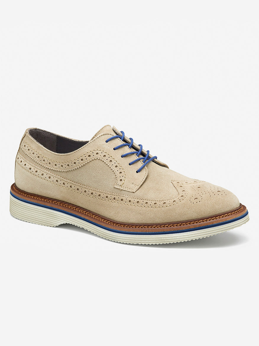 The J & M Collection Jenson Longwing in Taupe Italian Suede features blue laces, decorative perforations, a leather-covered footbed, and an EVA sole for comfort. Made from calfskin and displayed on a plain background.