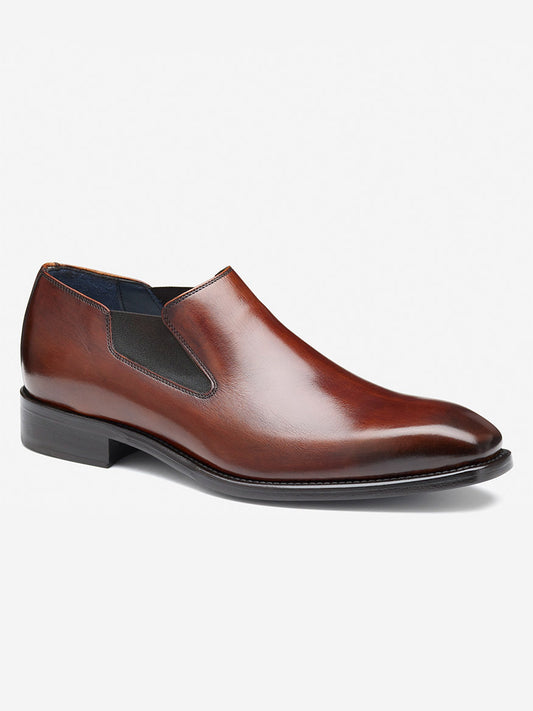 The J & M Collection Larson Slip-On, crafted in mahogany Italian calfskin, features a smooth finish and low heel. Displayed against a plain white background, this brown leather dress shoe is a testament to handcrafted elegance.