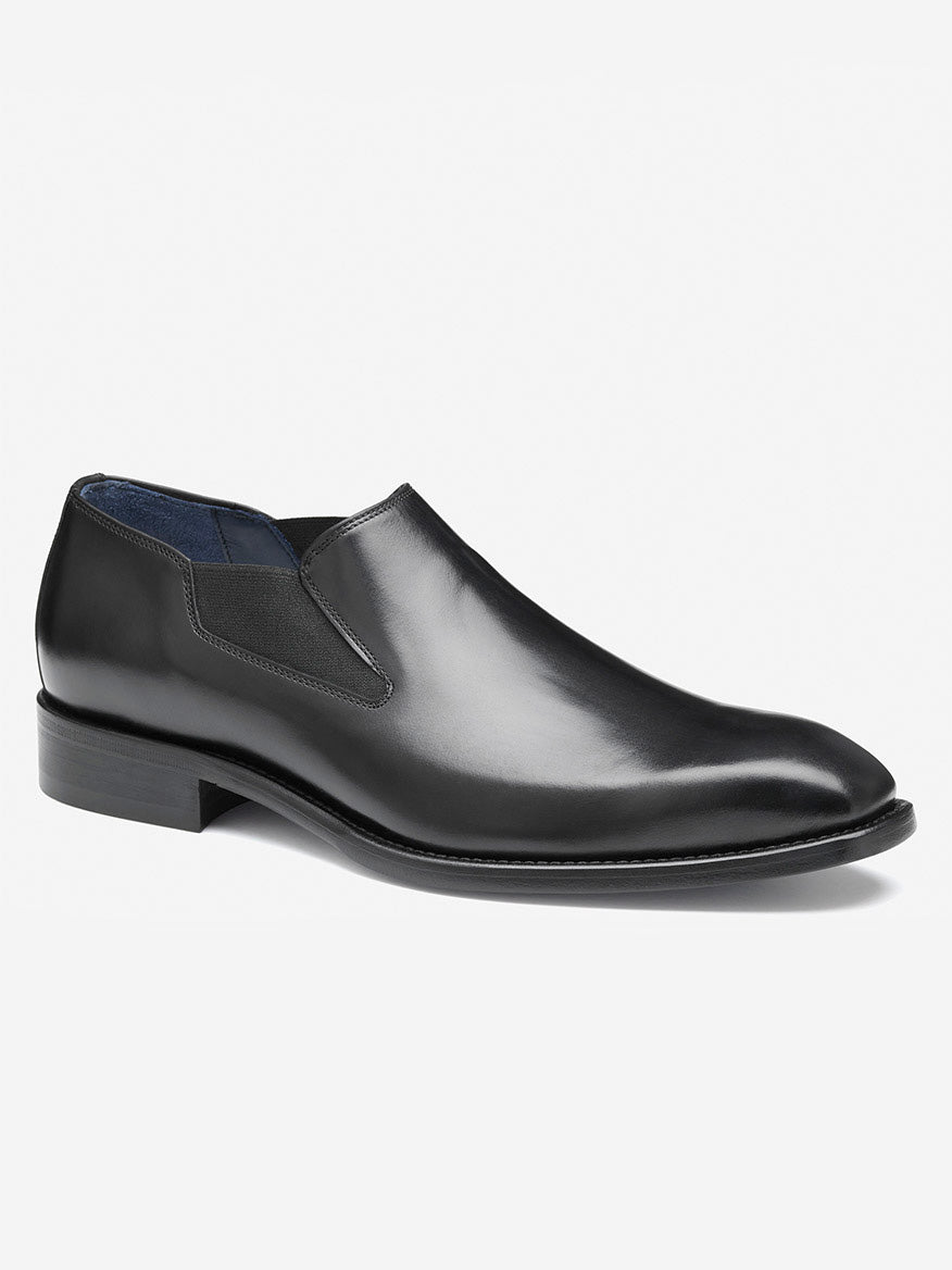 The J & M Collection Larson Slip-On in Black Italian Calfskin is a sleek dress shoe with a black leather design, featuring a low heel and elastic side panels.