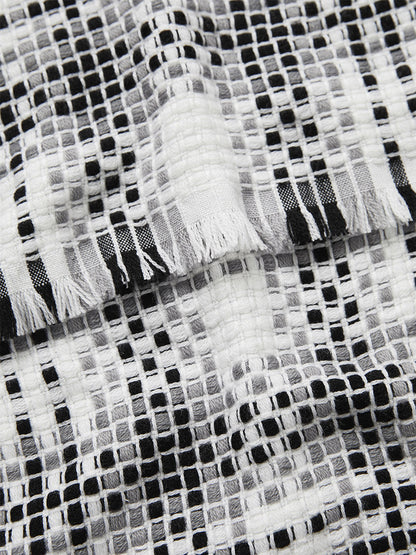 Close-up of a Jane Carr The Plaid Scarf in Black/White with frayed hems detail.