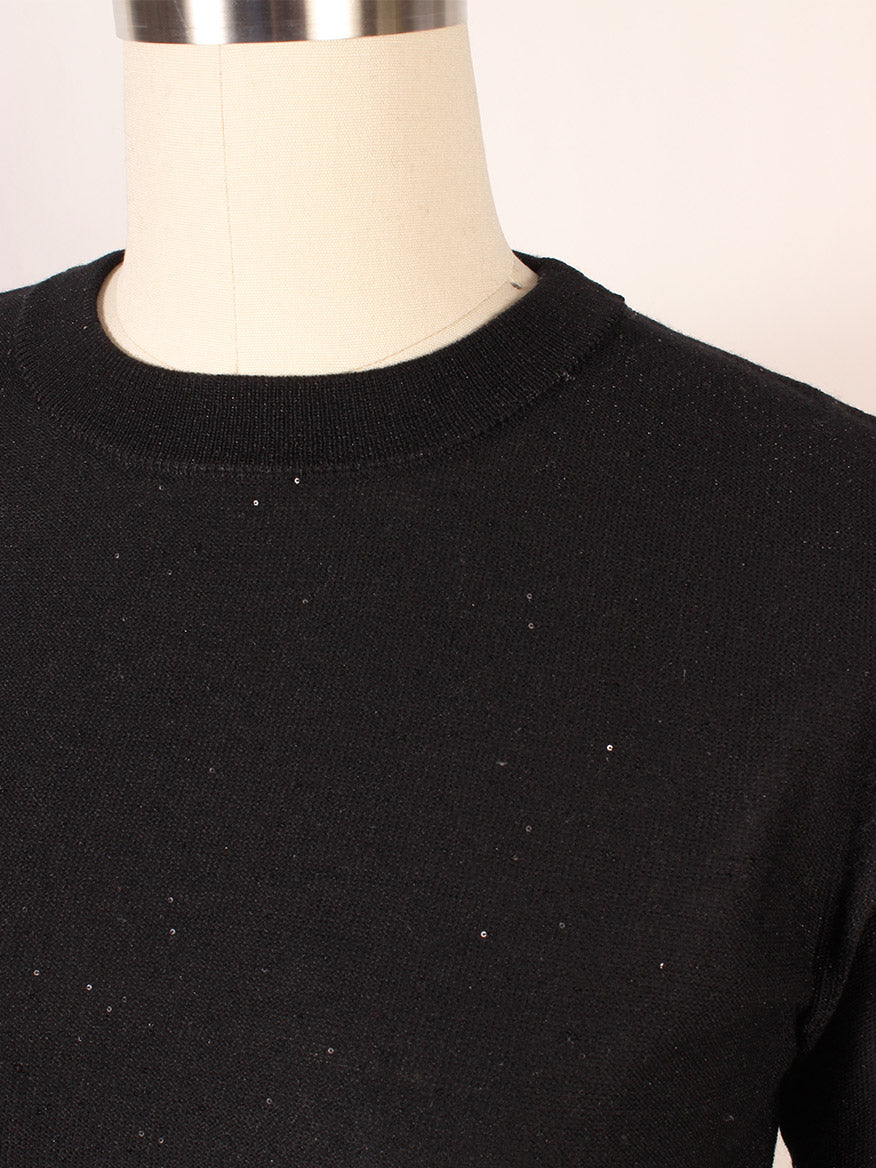 The Kinross Sequin Short Sleeve Crew in Black is showcased on a mannequin, highlighting its black knitted design with a crew neck, subtle sequins, ribbed trim, and short sleeves for elegance.