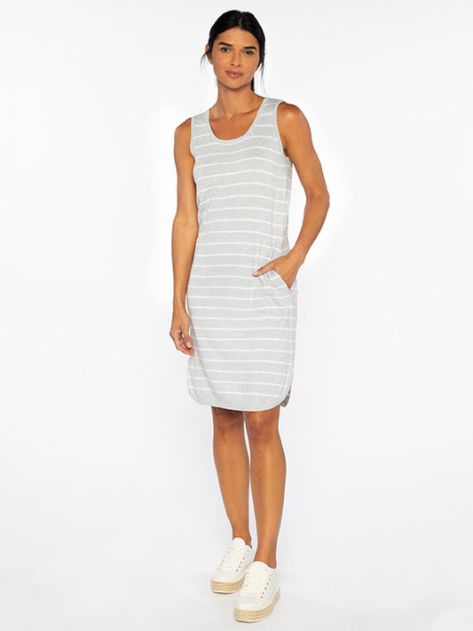 A person stands wearing a sleeveless, knee-length Kinross Stripe Tank Dress in Gris/White with side pockets and white sneakers against a plain white background.