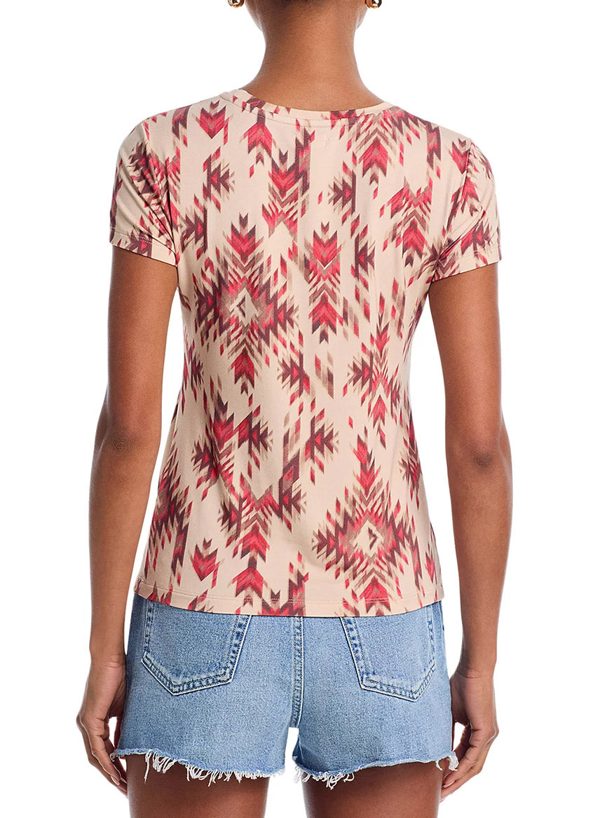 Someone shown from the back wears the L'Agence Ressi Fitted Tee in Tan Multi Ganado Print with blue denim shorts.