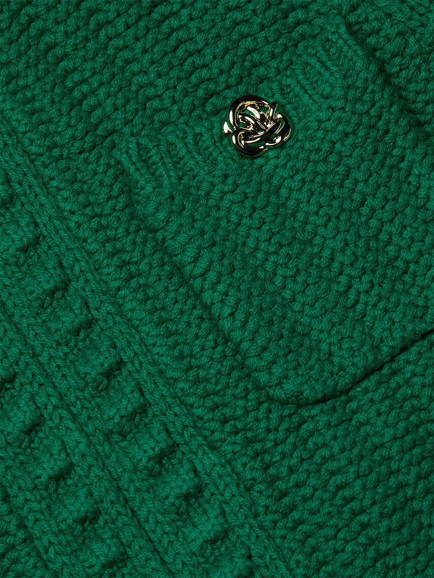 Close-up of the L'Agence Delilah Cropped Cardigan in Kelly Green/Gold Knot, showcasing its textured knit and a pocket with a gold decorative button.