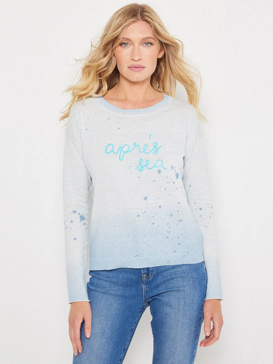 A woman stands against a white background wearing the Lisa Todd Apres Sea Sweater in Iced Blue and blue jeans.