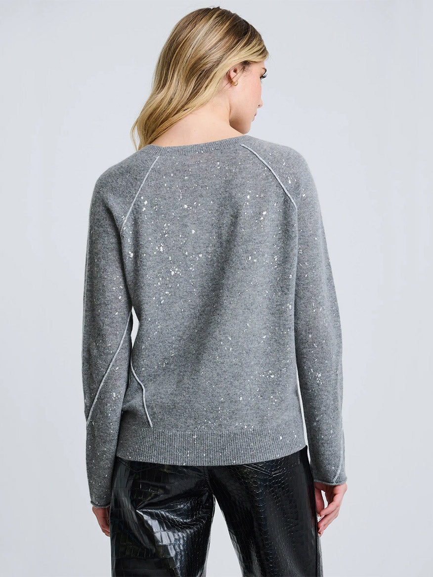 A person with long blonde hair is shown from the back, wearing the Lisa Todd Diamond Dust Sweater in Fog and black textured pants against a plain light background.