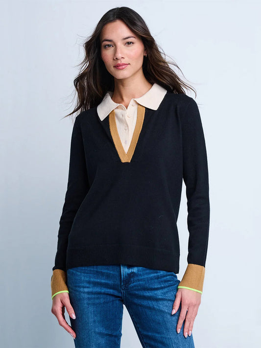 A woman wears the Lisa Todd Double Down Sweater in Black, featuring a tan collar and cuffs in a Cotton-Cashmere blend, paired with blue jeans, standing against a plain light background.