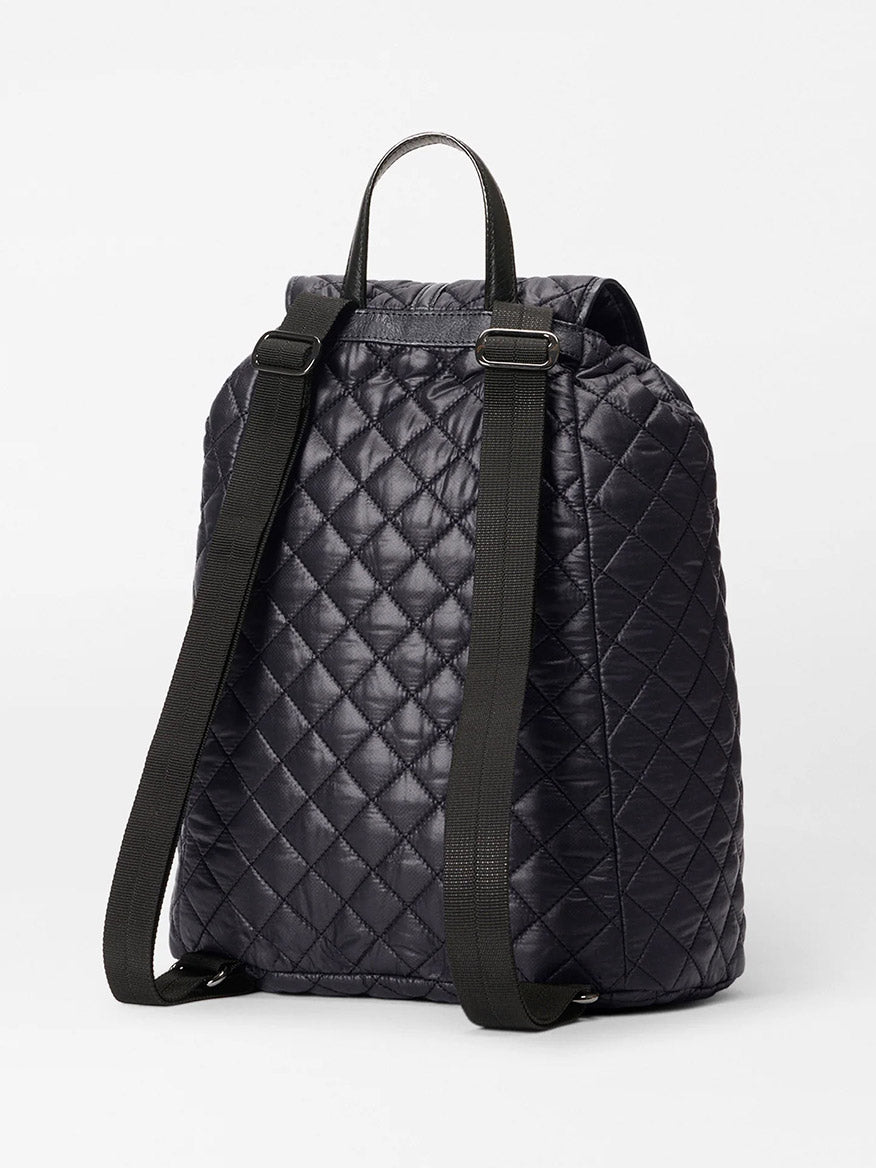 The MZ Wallace Astor Backpack in Black Oxford, shown from the back on a white background, features quilted black material, gunmetal hardware, adjustable shoulder straps, and a top handle.