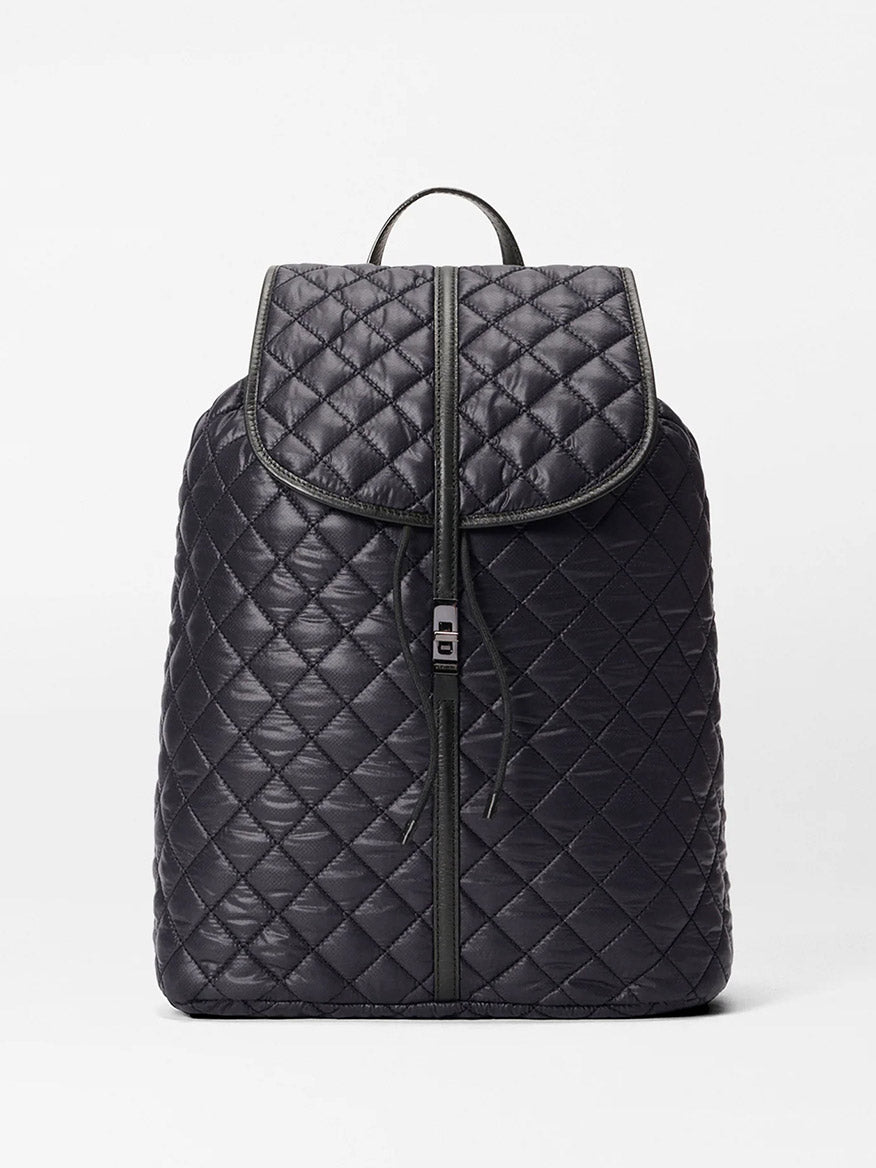 The MZ Wallace Astor Backpack in Black Oxford is a quilted laptop backpack with gunmetal hardware, flap closure, front zipper, and top handle—shown on a plain white background.