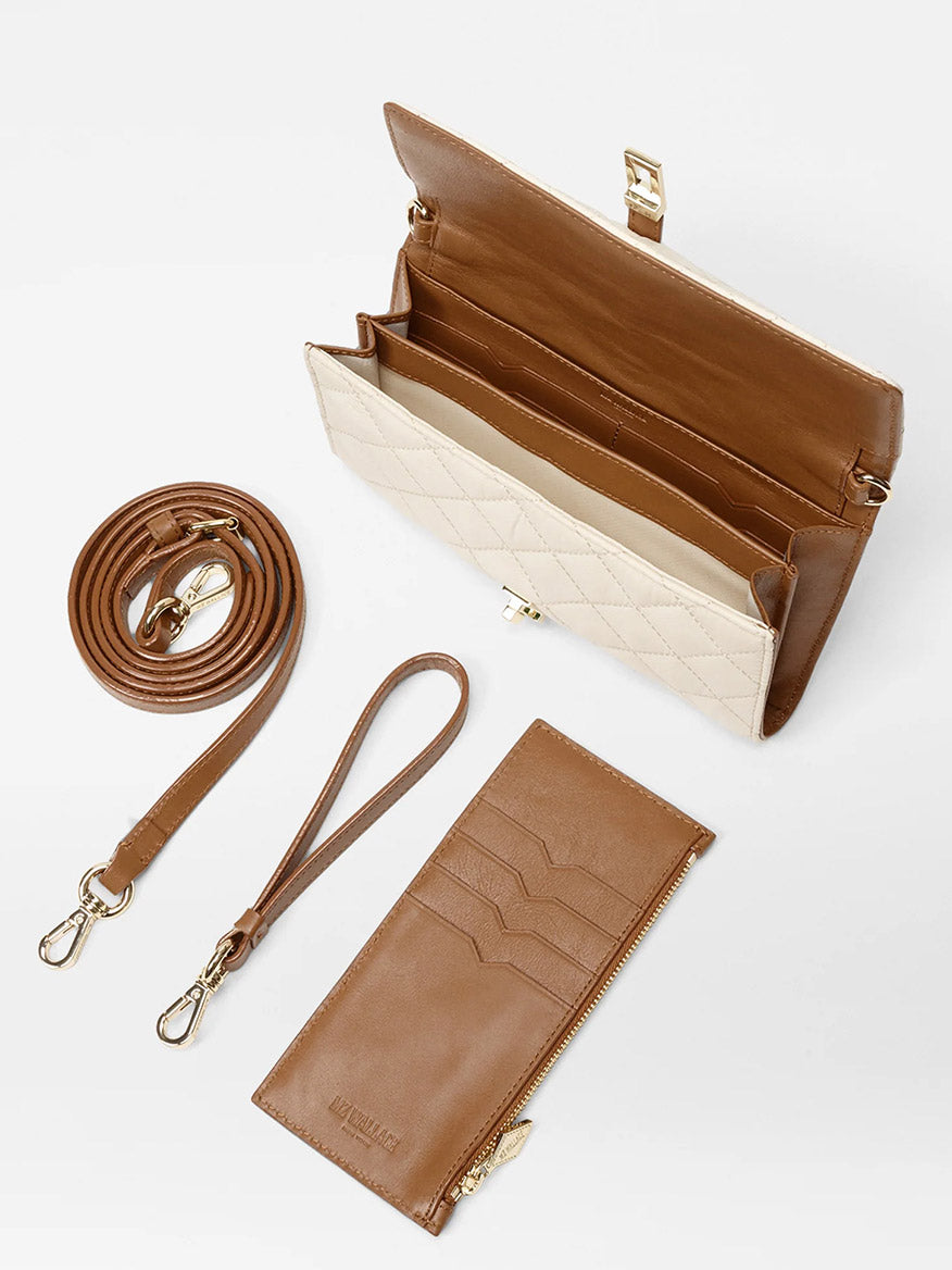 The MZ Wallace Astor Convertible Crossbody in Sandshell Oxford with Brown, featuring gold hardware, a detachable Italian leather strap, wristlet strap, and matching cardholder with zipper pocket, is displayed on a white surface.