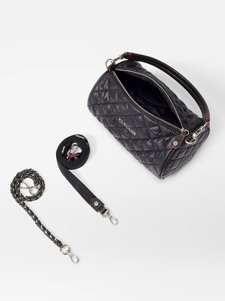 The MZ Wallace Crosby Barrel Crossbody in Black Oxford, featuring signature hardware, detachable straps, and a braided keychain, is displayed on a white surface.