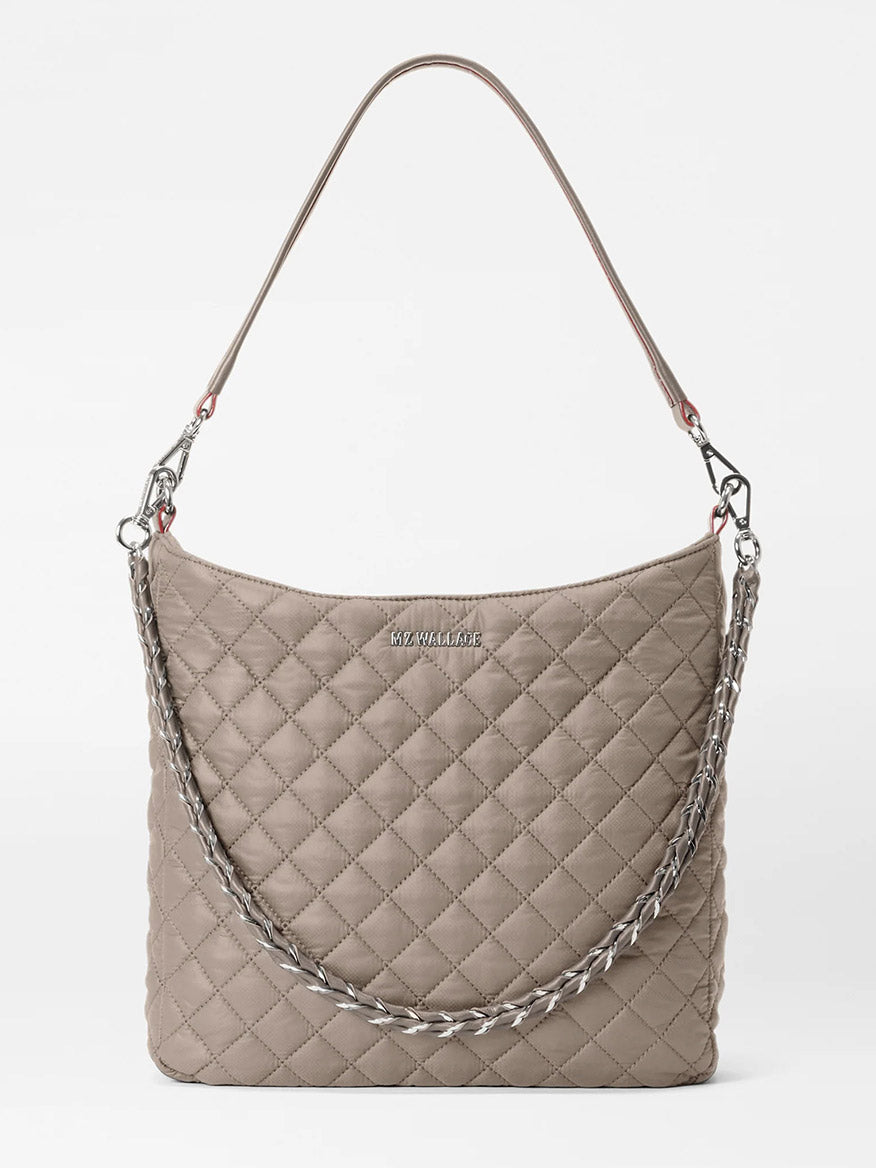 The MZ Wallace Crosby Hobo in Morning Dove Oxford, featuring quilted taupe leather with Italian accents, a silver chain and leather strap, plus a metal logo on the front, is displayed against a plain white background.