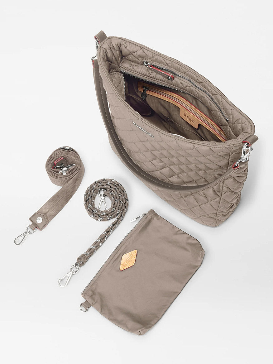 The MZ Wallace Crosby Hobo in Morning Dove Oxford features a quilted design, zippered top, Italian leather accents, detachable and braided straps, plus a small zip pouch, all shown on a white surface.