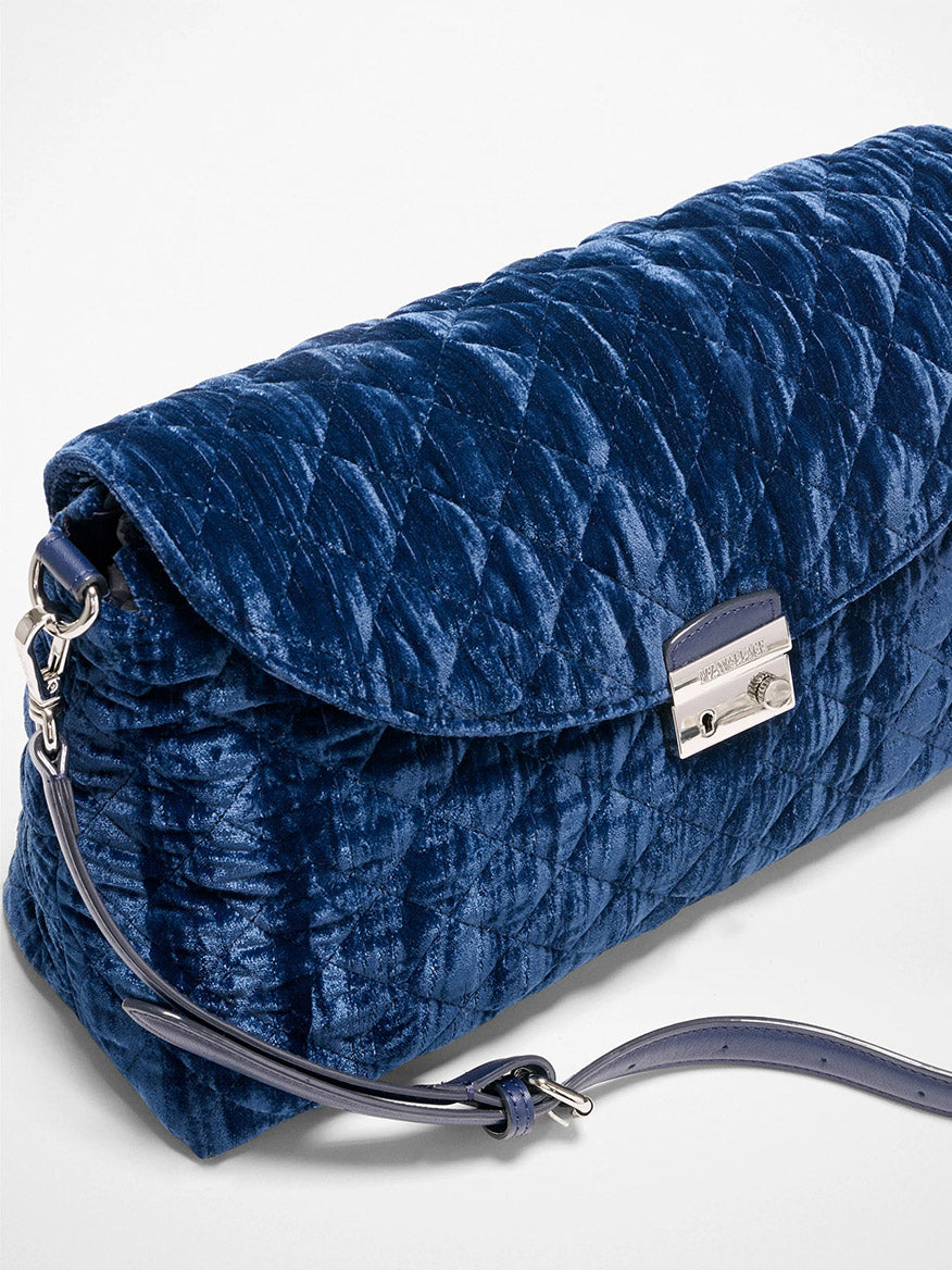 The MZ Wallace Crosby Lock Shoulder in Midnight Velvet is a quilted navy blue velvet clutch with a silver clasp, Italian leather trim, and a detachable matching shoulder or crossbody strap, shown on a white background.