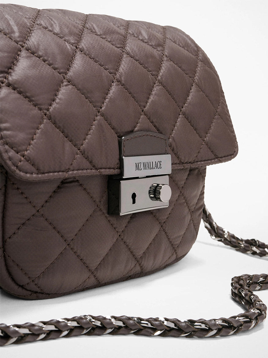 Close-up of the MZ Wallace Crosby Lock Small Crossbody in Espresso Oxford, featuring a quilted brown finish, silver chain strap, and clasp engraved with "MZ WALLACE" for a signature designer touch.