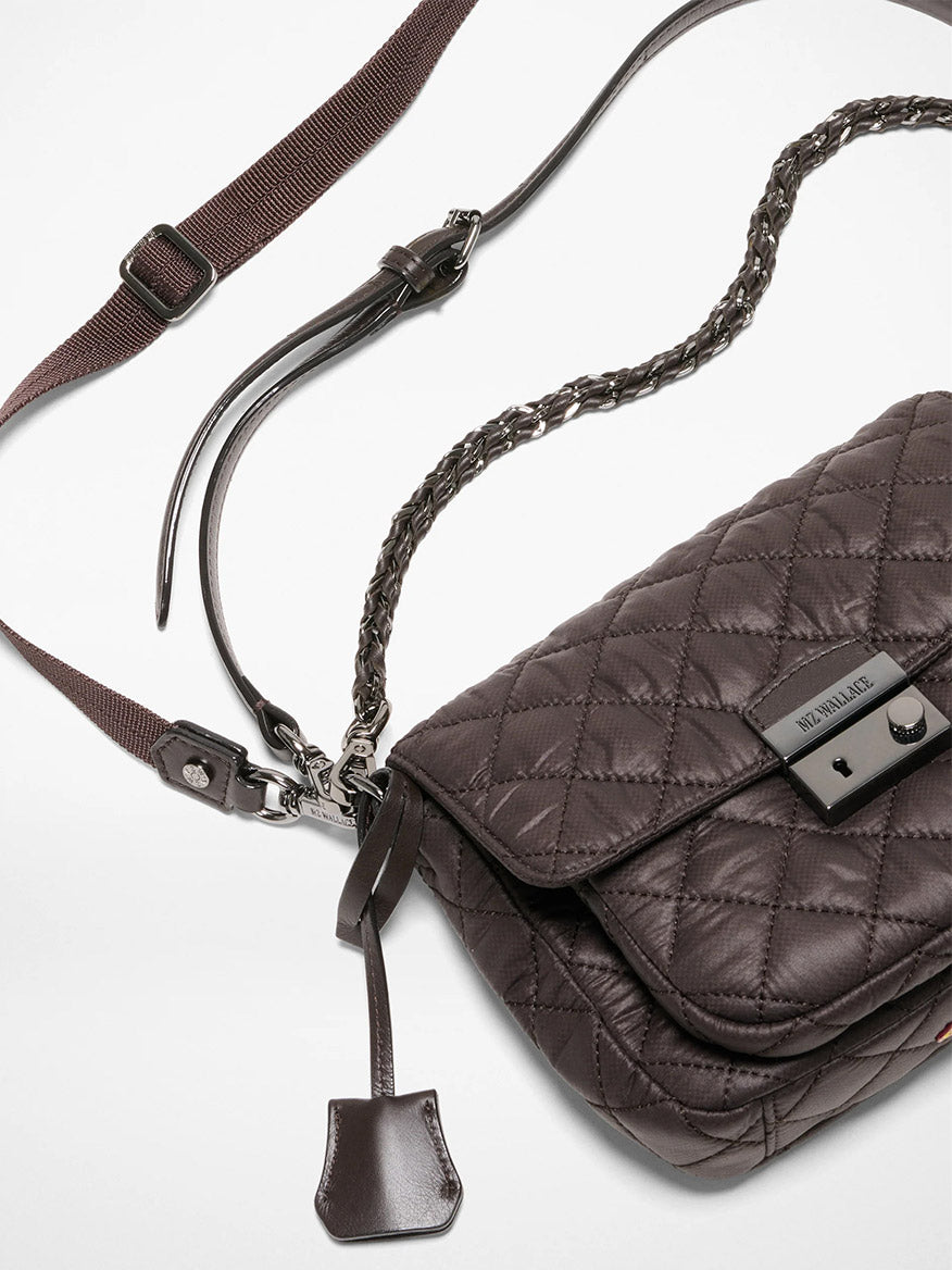 The MZ Wallace Crosby Lock Small Crossbody in Espresso Oxford features quilted dark brown leather, a metal clasp, braided leather strap, adjustable fabric strap, and a small leather tag, shown on a white background.