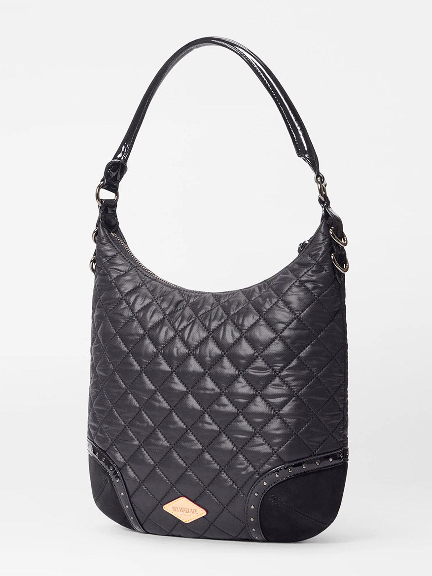 The MZ Wallace Multi Stud Crosby Sienna in Black Stud & Suede is a black quilted leather shoulder bag with Italian suede trim, single handle, curved top, metal studs on the corners, and a gold-tone brand plate on the front.