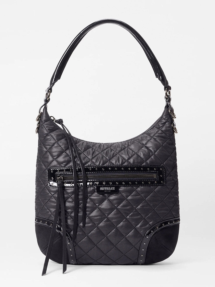 The MZ Wallace Multi Stud Crosby Sienna in Black Stud & Suede is a black quilted shoulder bag featuring a top handle, front zippered pocket, decorative studs, suede details, fabric tassel accent, and an adjustable shoulder strap.
