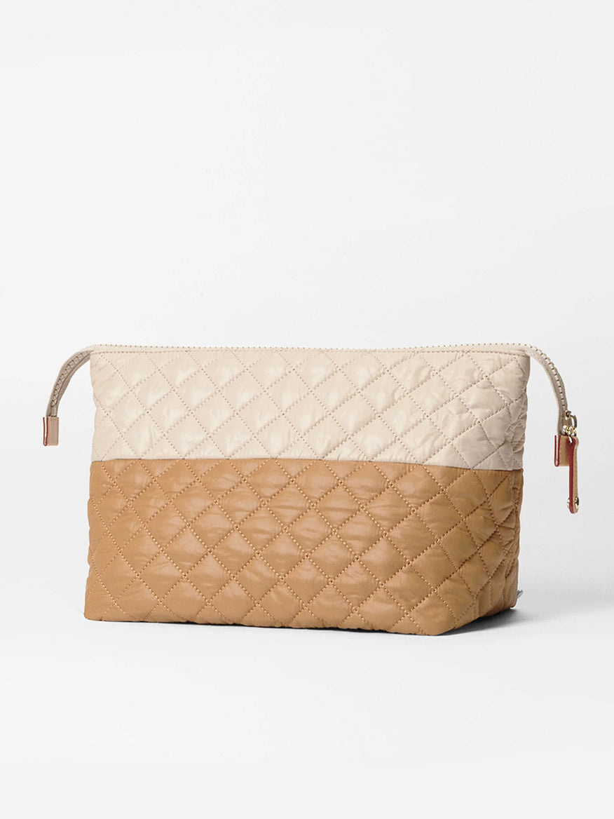 The MZ Wallace Large Zoey Cosmetic in Buff/Caramel Oxford is a quilted, rectangular bag with a beige and light brown design, gold zipper pull, and ample space—ideal for storing full-size cosmetics when traveling.