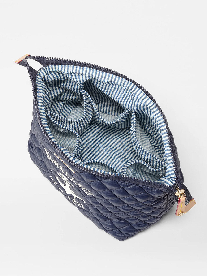 The MZ Wallace Large Zoey Cosmetic in Anchor Oxford is a navy quilted pouch with a zippered top, blue and white striped interior, and multiple compartments—perfect for organizing essentials when traveling.