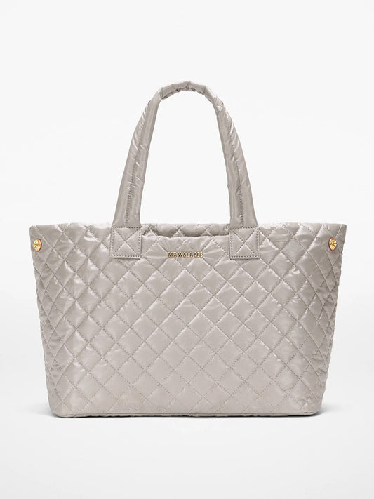 The MZ Wallace Medium East West Metro Tote in Sable Pearl Metallic Oxford features quilted silver-gray fabric, Italian leather trim, dual handles, gold-tone hardware, and a subtle front logo—stylish and ideal as a laptop bag.