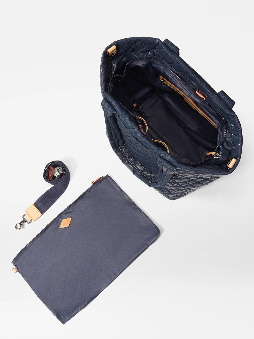 The MZ Wallace Medium Metro Tote Deluxe in Ink Liquid Oxford features a navy quilted design, dark interior, matching detachable strap, and separate zippered pouch—versatile style for travel or everyday use.