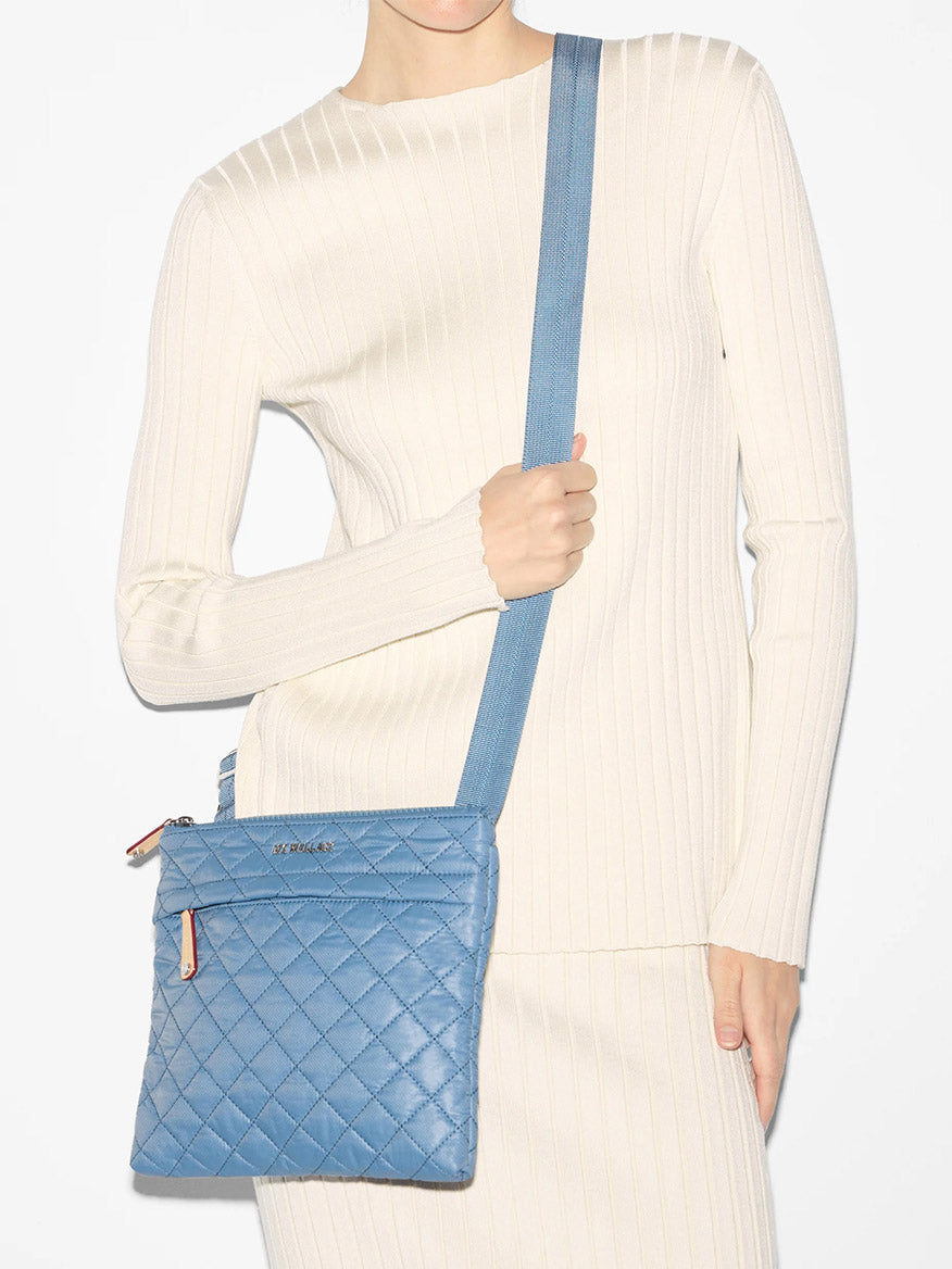 Woman showcasing a blue quilted MZ Wallace Metro Flat Crossbody in Cornflower Blue Oxford.