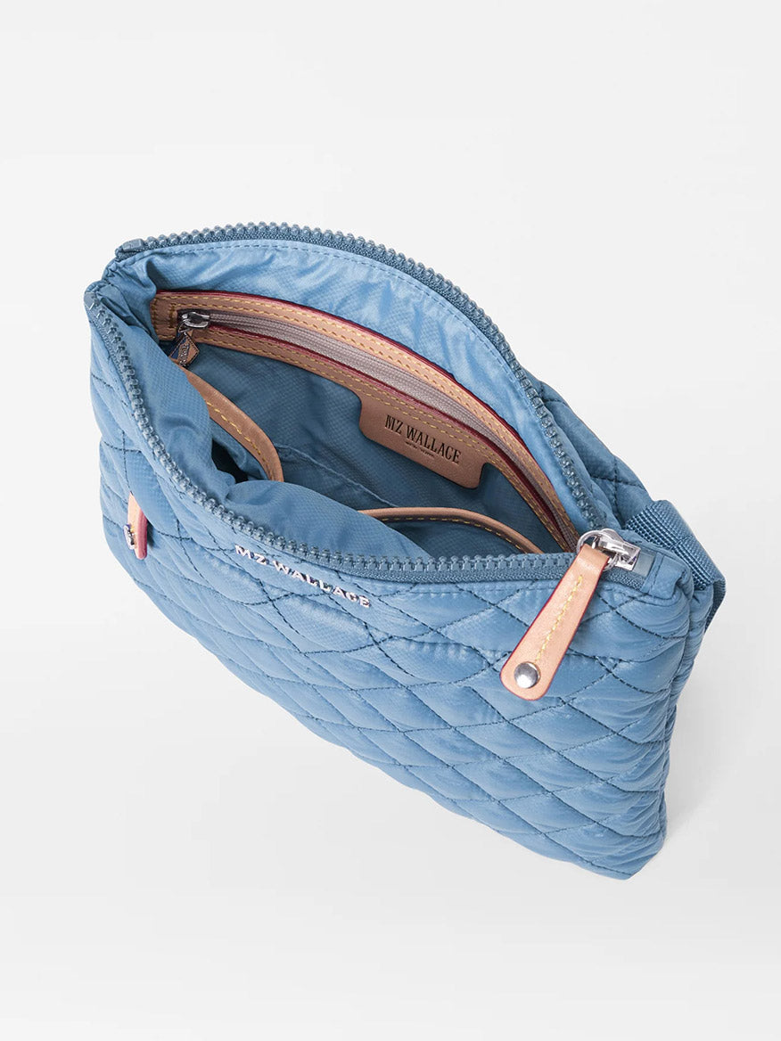 Open MZ Wallace Metro Flat Crossbody in Cornflower Blue Oxford with a brown leather trim and zipper closure on a white background.